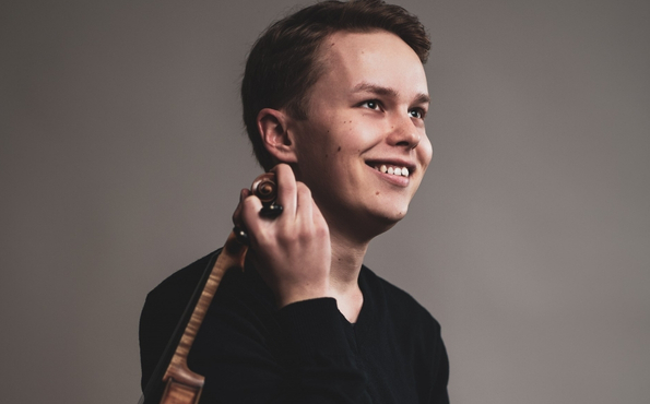 Lähikuvassa nuori mies viulu kädessä.